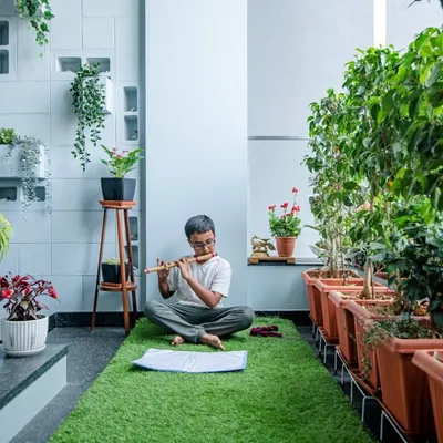 Close to divinity. We create spaces that encourage mindfulness and peace. This serene corner, with its lush green carpet and rows of potted plants, is a perfect spot for meditation or playing music.