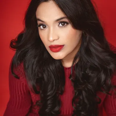 A powerful close-up portrait against a vibrant red studio backdrop. The model's direct gaze and the rich color saturation create a bold and confident statement.