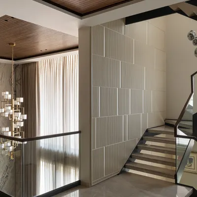This sculptural staircase connects four floors, acting as the central spine of the home. Its floating design, framed by fluted wall panels and a modern chandelier, creates a sense of lightness and vertical grandeur.