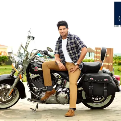 A classic look for Dulquer Salmaan from the Otto campaign. We styled him in a timeless plaid shirt, white tee, and khaki trousers for this shot with a Harley Davidson, creating an effortlessly cool and rugged menswear look.
