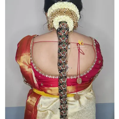 A traditional South Indian bridal hairstyle for Akshatha's muhurtham, featuring a long braid adorned with intricate hair jewellery and a jasmine flower arrangement.