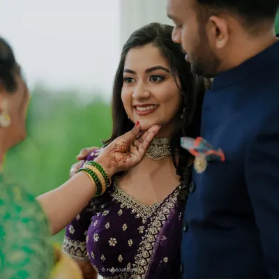 A sweet, candid moment. The bride is wearing a delicate Kundan choker that perfectly complements her embroidered purple lehenga.