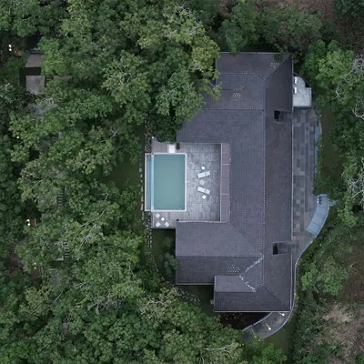 An aerial top-down view of The Leaf Poomala, a hospitality project in Kerala. The design places a private pool deck right at the edge of the forest, allowing guests to feel completely immersed in the dense, tropical greenery.