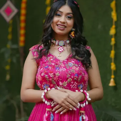 A radiant Haldi bride. This soft glam look features a pop of pink on the eyes, glowing skin, and a modern braided hairstyle, perfectly matching her vibrant outfit and shell jewelry.
