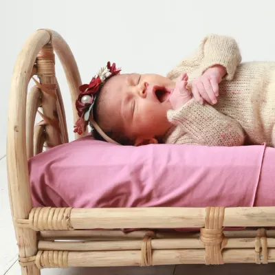 A sleepy yawn from a 21-day-old newborn. Even as they get a little older, we can still capture these incredibly precious and delicate moments. This little one is resting comfortably on a miniature rattan bed, a popular prop for my newborn sessions.