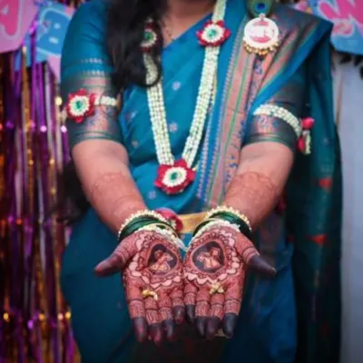 A beautiful shot of a mom-to-be showcasing her baby shower mehendi. The design includes portraits of a couple, celebrating their journey to parenthood.