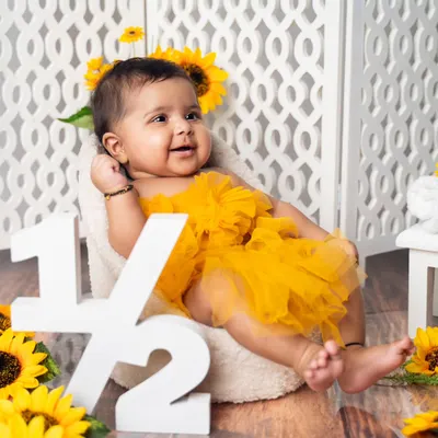 Halfway to one. This six-month sitter session celebrates a huge milestone with a bright and cheerful sunflower theme, complete with a '1/2' sign.