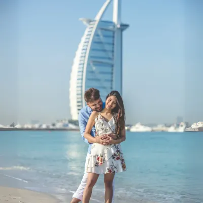 An iconic Dubai pre-wedding portrait. The couple shares a happy moment on the beach, with the magnificent Burj Al Arab standing tall in the background.