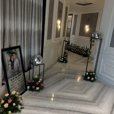 An elegant hallway decoration for a home event, featuring a personalized welcome sign, disco balls, and floral arrangements.