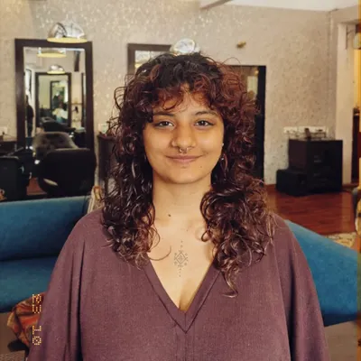 The final result of a tailored curly haircut. This front view shows how the layers and bangs frame her face beautifully, creating a balanced and flattering shape for her curls.