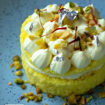 Our Rasmalai Cheesecake, a true fusion masterpiece. This dessert features layers of saffron-infused sponge and creamy cheesecake, topped with pistachios and delicate silver leaf.