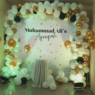 An elegant black, white, and gold balloon arch for Muhammad Ali's Aqeeqah ceremony. The starry backdrop and simple color scheme create a refined and celebratory setting for this important religious event.