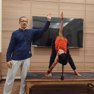 An instructor demonstrates the correct alignment for Trikonasana (Triangle Pose) while a student practices. This shows my emphasis on precise, guided instruction to ensure students understand the mechanics of each asana.