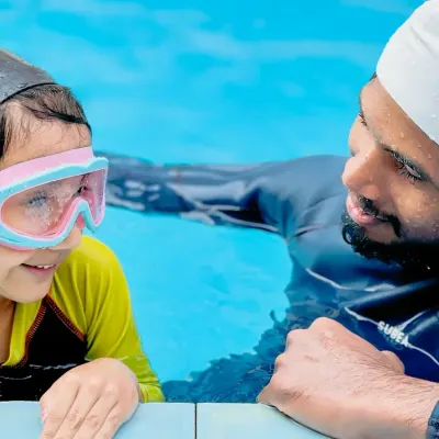 A coach provides one-on-one encouragement to a young swimmer at the edge of the pool. These moments of personal connection are key to building a child's confidence.