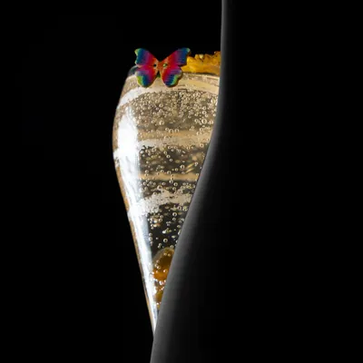 An interplay of sensational silhouettes. This shot captures the elegant form of our Peach and Lavender Bellini next to the bottle, highlighting its delicate bubbles and butterfly garnish.