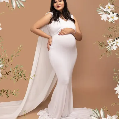 The definition of elegance. This mother-to-be is wearing a beautiful white cape gown from my studio collection, creating a classic and graceful silhouette against a simple backdrop.