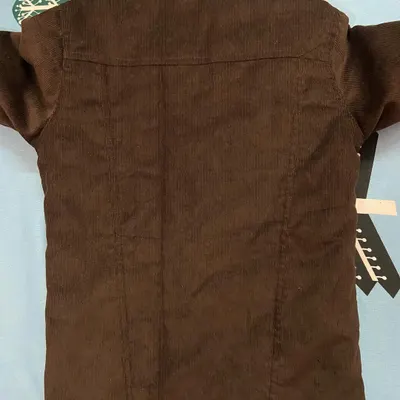 The back view of the custom brown corduroy jacket, showing the clean lines, yoke construction, and the rich texture of the corduroy fabric.
