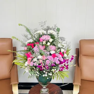 A large and impressive vase arrangement with a mix of fresh carnations, roses, and orchids. This is ideal for decorating a clubhouse for a party or as a statement piece for an office reception.