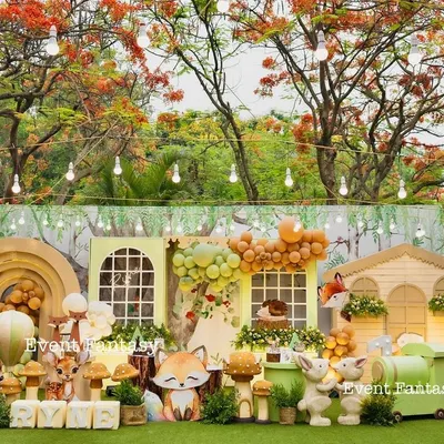 A breathtaking, wide-angle view of Ryne's woodland party. The entire setup is framed by beautiful flowering trees, featuring a charming house backdrop, 3D animal cutouts, and whimsical props for a complete fantasy world.