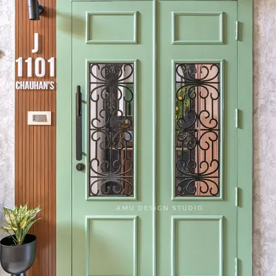 A statement entrance door painted in a refreshing sage green, featuring classic paneling and wrought iron grilles for a touch of vintage elegance.