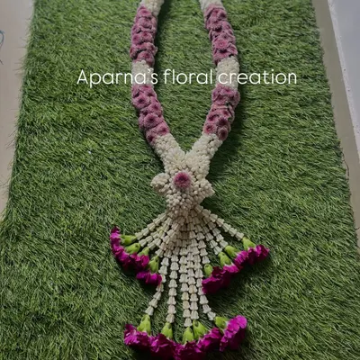 This is a beautifully crafted Thai-style garland. The intricate weaving technique and the combination of purple and white flowers make it a very special and eye-catching creation.