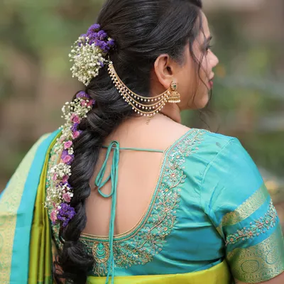 A stunning Marathi bridal hairstyle. This intricate braid is adorned with fresh purple and white flowers and a traditional hair accessory, creating a look of pure elegance.