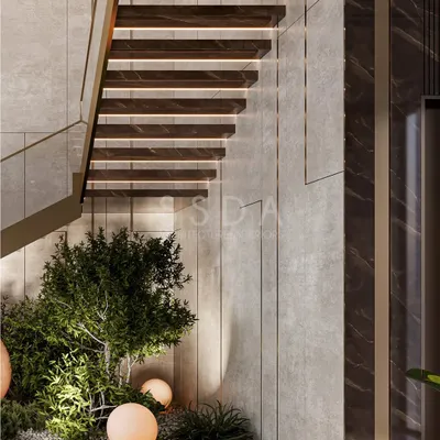 We believe greenery shouldn't be confined to the outdoors. In this villa, we designed a small garden bed directly beneath the floating staircase, turning a simple circulation space into a vibrant focal point with lush plants and soft, spherical lights.
