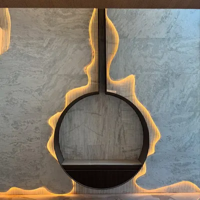 A close-up of a bespoke fireplace feature where we carved into a stone wall and used backlighting to create a fluid, glowing outline. This detail transforms a functional element into a central art piece.