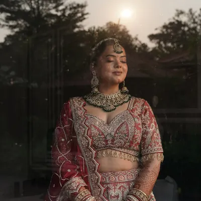A moment of serene beauty before the ceremonies begin. We gave this bride a radiant, flawless finish with a soft focus on the eyes, perfectly complementing her intricate red and pink lehenga.