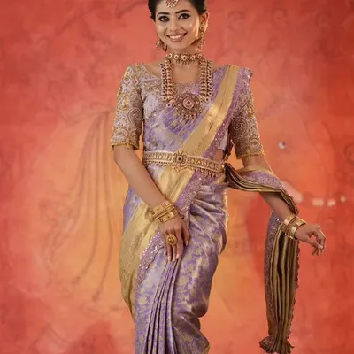 A model looking regal in a lavender silk saree, paired with a custom blouse featuring heavy gold embroidery on the sleeves.