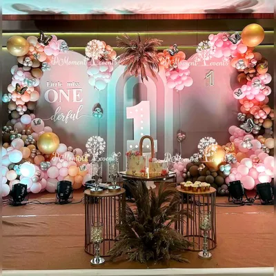 An elegant Boho Rainbow stage for a twins' first birthday, featuring a "Little Miss ONEderful" backdrop, pampas grass, and a sophisticated palette of dusty rose, brown, and gold balloons.