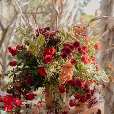 A lush floral arrangement from our 'Regal Rustic Reverie' wedding. The combination of deep red roses, birds of paradise, and other exotic greens created a look that was both dramatic and incredibly elegant.