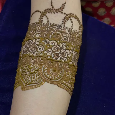 A bridal Indian arm band design with delicate hanging chains and intricate floral patterns.