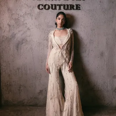 An exquisite blend of tradition and modernity, this ivory sharara set is a masterpiece of intricate craftsmanship. It features a structured, embellished blazer, a coordinating bustier, and flowing sharara pants.