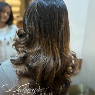 This is what balayage dreams are made of. We created these soft, dimensional layers of color to melt into her natural hair, finished with bouncy curls to show off the seamless blend.