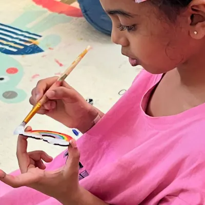A close-up from a fun-filled birthday party! This little artist is adding the final touches to her rainbow cutout. Our art activities are a perfect, engaging addition to any celebration.
