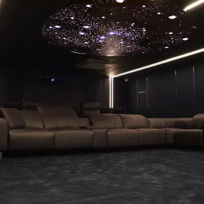 A view of a completed custom home cinema featuring luxury recliner seating and a starlit ceiling. This setup is designed for ultimate comfort and immersion, making it the perfect private screening room.