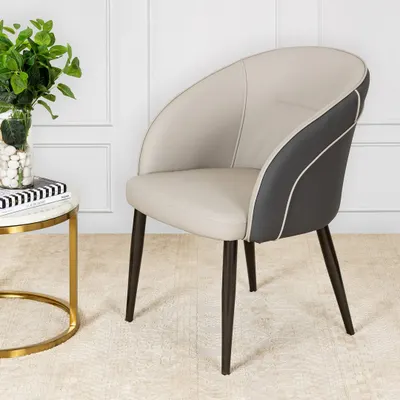 This chair is the definition of quiet luxury. Upholstered in smooth cream and dark grey leather with sculptural curves and elegant piping, it’s the kind of piece that belongs in a well-curated, modern space.
