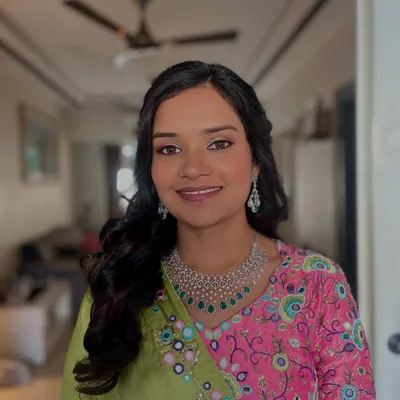 A perfect example of a radiant Haldi ceremony look. The makeup is minimal and fresh, letting the bride's natural glow shine through, complemented by soft curls.