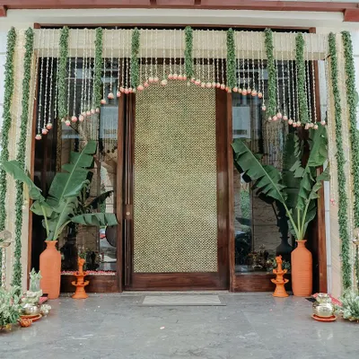 A beautiful and traditional entrance for a housewarming ceremony. We used garlands of jasmine and lotus buds, large banana plants in terracotta vases, and brass diyas to create a truly auspicious welcome.