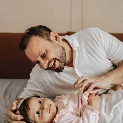 A playful father-daughter moment captured during a lifestyle session at home. The genuine laughter makes this photo special.