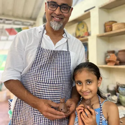 A father and daughter duo beaming with pride as they hold up the small clay figures they made together. These sessions are all about creating shared memories.