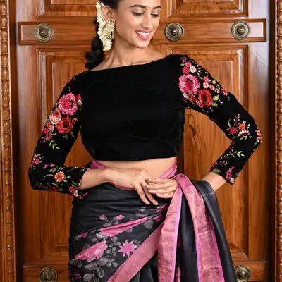 This black velvet blouse is the epitome of elegance. The full sleeves are adorned with intricate floral embroidery in shades of pink and red, making it a perfect partner for both silk and designer sarees.