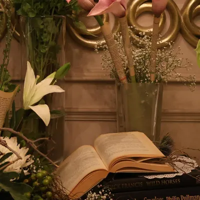 A close-up of our vintage-themed decor, featuring pink calla lilies and an open book set against a backdrop of lush greenery. This type of arrangement is perfect for creating an elegant, literary feel.