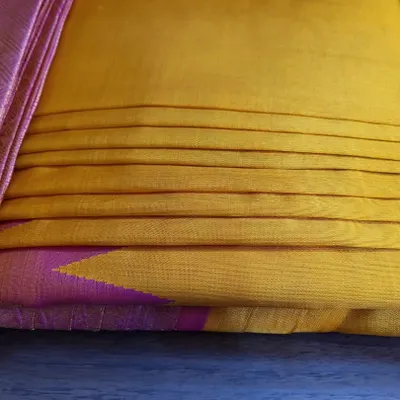 A close-up of a client's yellow and pink silk saree after my pre-pleating and box folding service.