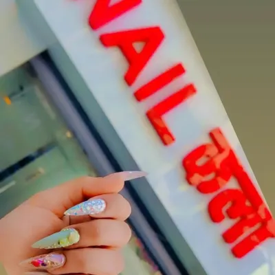 A client showing off her custom nail art right outside our studio. This set features long stiletto nails with a mix of glitter and encapsulated floral designs.