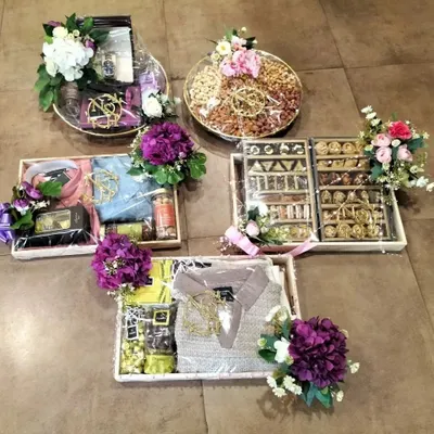 A complete overview of a wedding trousseau project, featuring coordinated gift boxes and platters. We pack a variety of items including clothing, dry fruits, and sweets, unified by a consistent theme and floral decor.