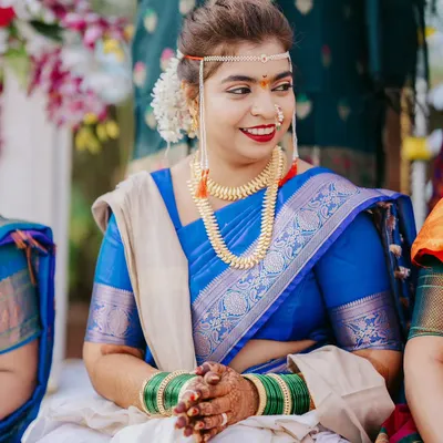 A lovely candid portrait of a bride in a royal blue saree, smiling during her Maharashtrian wedding ceremony.