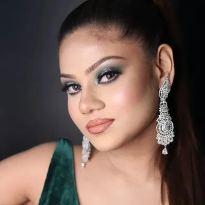 A stunning cocktail makeup look with dramatic green smokey eyes, a flawless base, and a high ponytail.