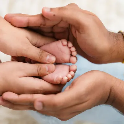 A classic and powerful shot of a newborn's tiny feet being held safely in their parents' hands.
